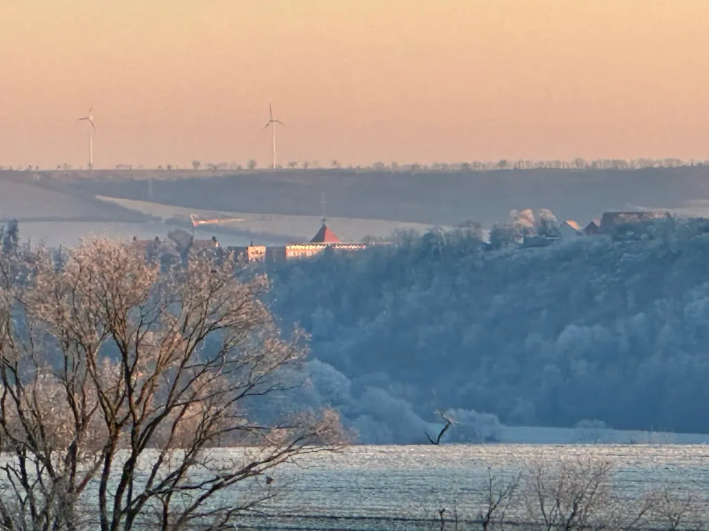 Winterlandschaft mit Burg und Windrädern am Horizont