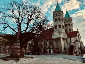 Romanische Kirche mit grünen Doppeltürmen